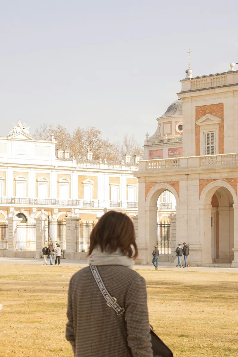 The pink-and-cream façade of the Royal Palace of Aranjuez reflected beside the Tagus river gardens